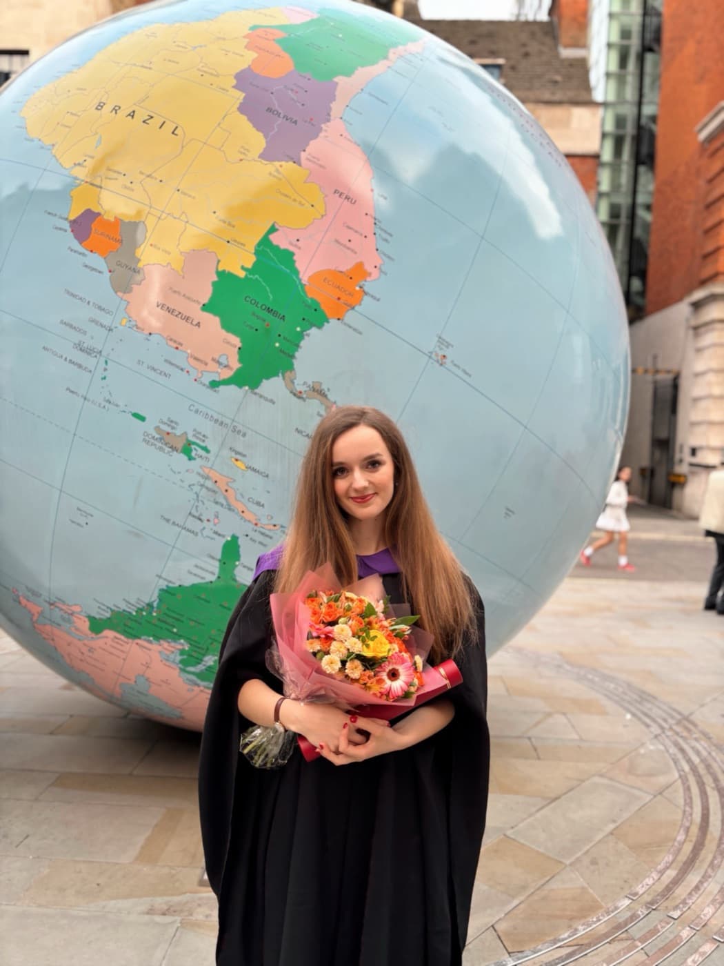 Annamaria at LSE graduation beside the globe sculpture