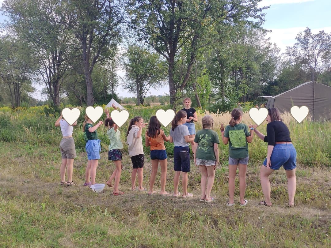 Children at an outdoor scout activity with faces covered for privacy